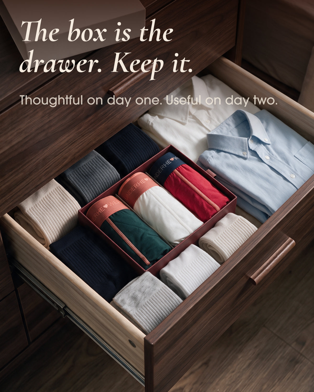 An underherwear gift box organizing rolled boxer briefs beside socks and a shirt in a dresser drawer.